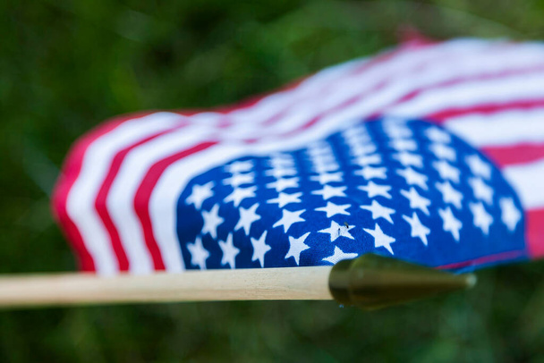 Uma pequena bandeira americana repousa na frente de um herói caído em um cemitério militar - Foto, Imagem
