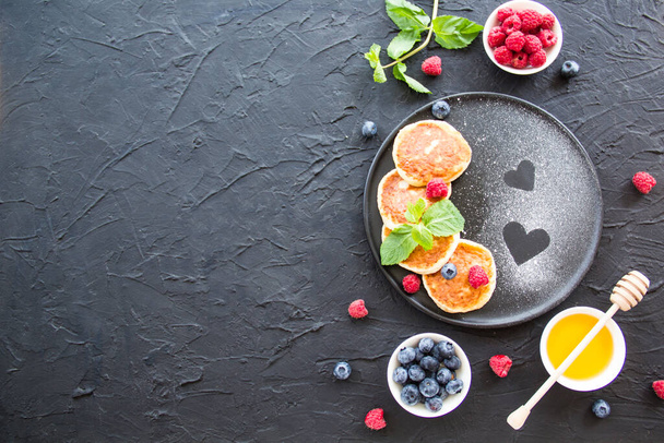 Здоровий сніданок з сирними млинцями, ягодами та медом. Творче атмосферне оздоблення
 - Фото, зображення