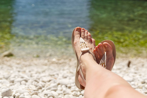 beautiful legs on a rocky beach. woman feet on front of sea rocky beach. - Photo, image