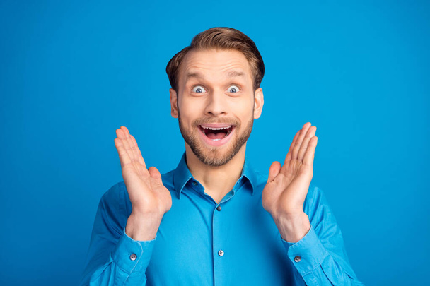 Photo of impressed cheerful man arms palms up open mouth look camera isolated on blue color background - Fotografie, Obrázek