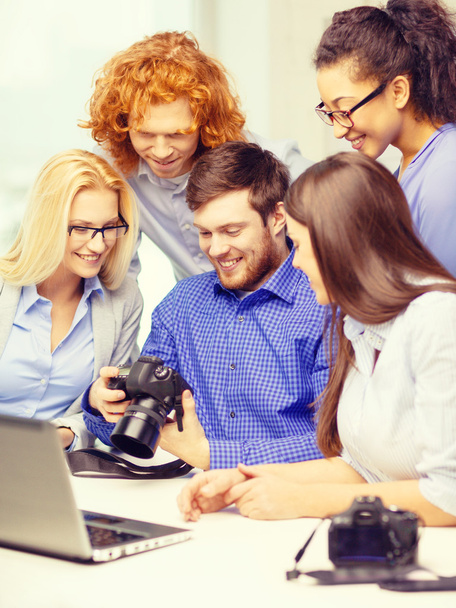 smiling team with laptop and photocamera in office - 写真・画像