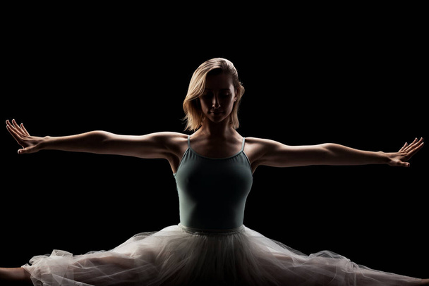 ballerina with a white dress and black top posing on black background. side lit silhouette - Fotó, kép