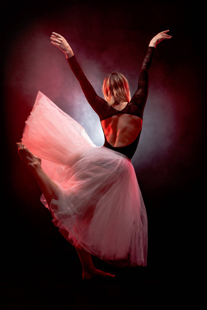 ballerina with a white dress and black top posing on red smoke background. - Photo, Image