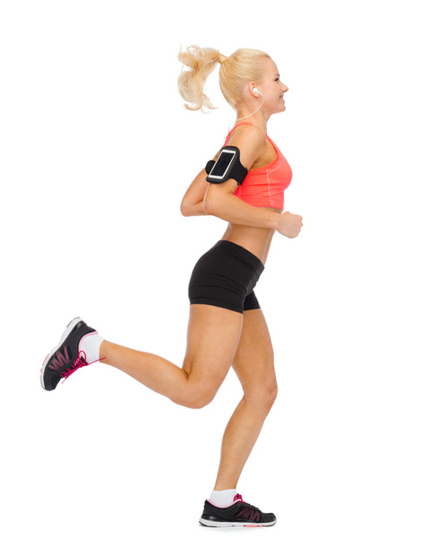 sporty woman running with smartphone and earphones - Zdjęcie, obraz