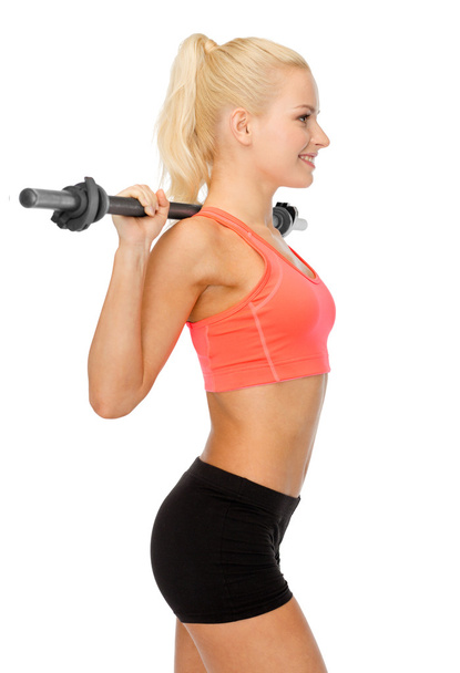 smiling sporty woman exercising with barbell - Foto, Imagem