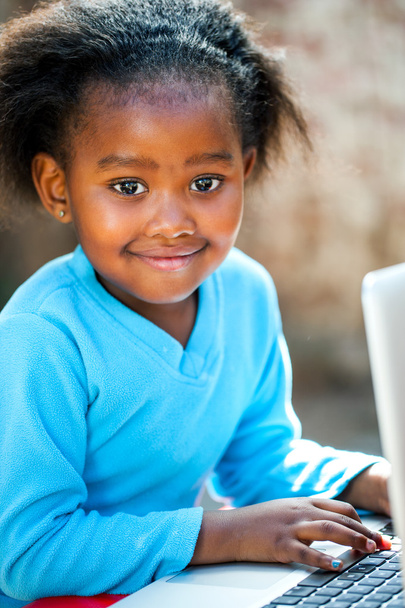schattig Afrikaanse meisje te typen op laptop. - Foto, afbeelding