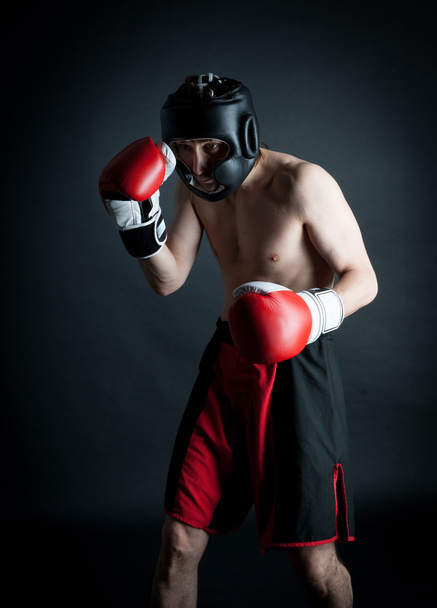 Man in helmet boxing in black background - Zdjęcie, obraz