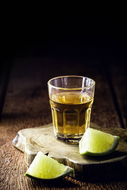 glass of alcoholic drink with lemon, distilled from sugar cane, called in Brazil "pinga" or "cachaca", copyspace - Photo, Image