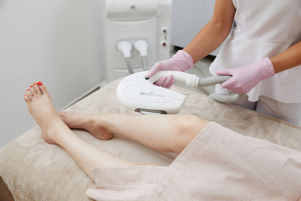 Vista parcial de la mujer que recibe depilación por depilación láser en la pierna en un salón - Foto, Imagen