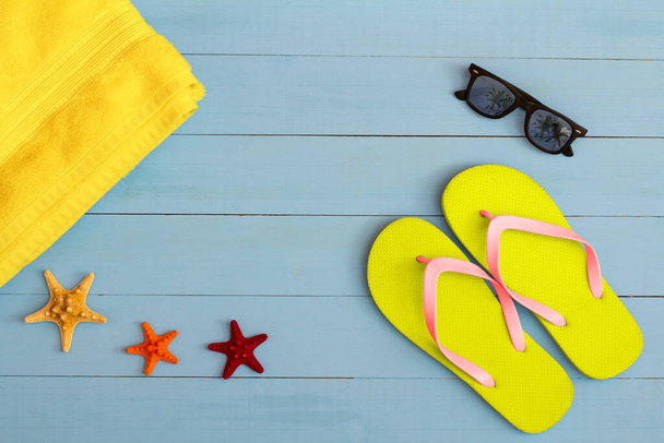 Heure d'été sur une vue fraîche sur la table en bois peint bleu clair avec lunettes de soleil, tongs, serviette et étoile de mer - Photo, image