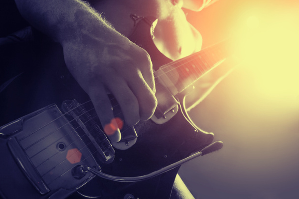 Чоловік грає на електричній гітарі в чорно-жовтому
 - Фото, зображення