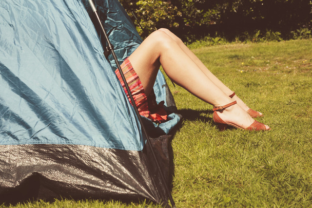 Young woman raising her legs from inside a tent - 写真・画像