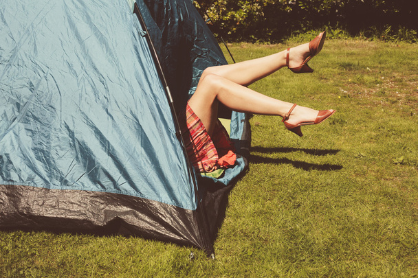 Young woman raising her legs from inside a tent - Fotoğraf, Görsel