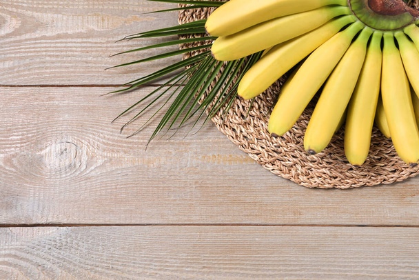 Bunch of ripe baby bananas on wooden table, above view. Space for text - Foto, imagen