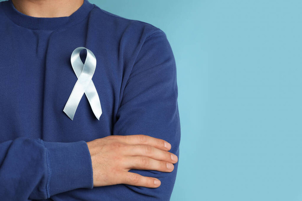 Closeup view of man with ribbon on light blue background, space for text. Urology cancer awareness - Foto, immagini
