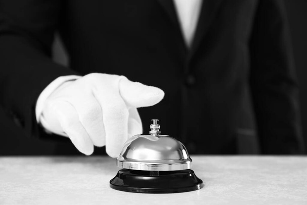 Butler ringing service bell at table on black background, closeup - Fotografie, Obrázek