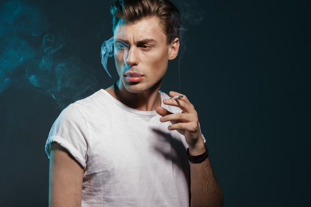 Handsome young man smoking cigarette - Photo, image