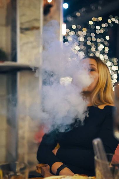 Mujer fuma narguile en bar salón. - Foto, imagen
