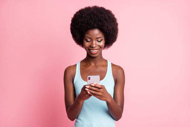 Photo of optimistic cute brunette curly lady hold telephone wear blue top isolated on pastel pink color background - Valokuva, kuva