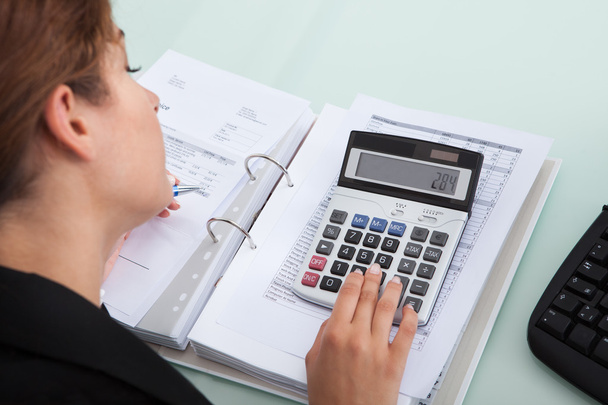 Businesswoman Calculating Bills At Desk - Photo, image
