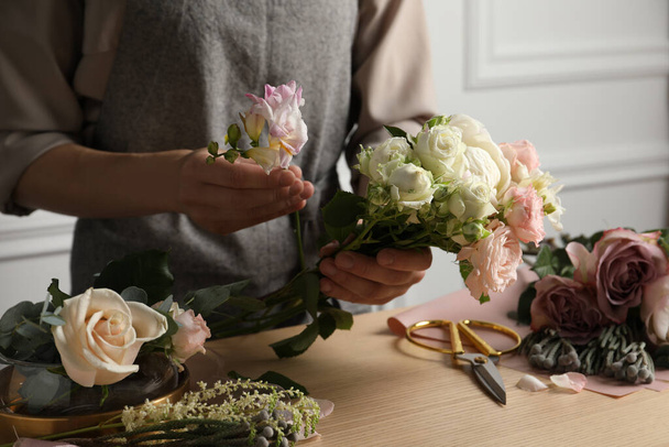 Florist creating beautiful bouquet at wooden table indoors, closeup - Foto, afbeelding