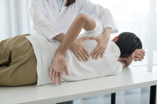 Fisioterapeutas femeninas brindan asistencia física a pacientes masculinos con lesiones en la espalda masajes de espalda para la relajación y la recuperación muscular en el centro de rehabilitación. - Foto, imagen