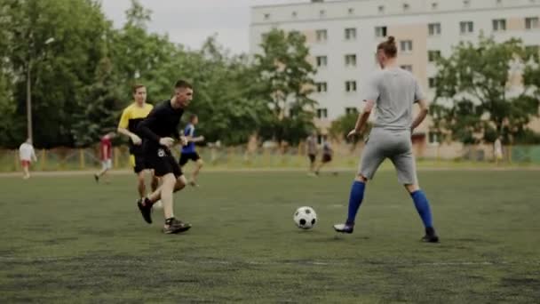 Игроки футбольной команды тренируются на футбольном поле в жилом районе города и практикуются в игровых моментах. Медленное движение - Кадры, видео