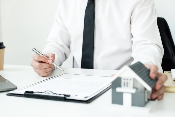 Agenten, die in Immobilieninvestitionen und Hausversicherungen arbeiten, unterzeichnen Verträge im Einklang mit den Verträgen über den Kauf von Eigenheimen, die Käufe für Kunden genehmigen. - Foto, Bild