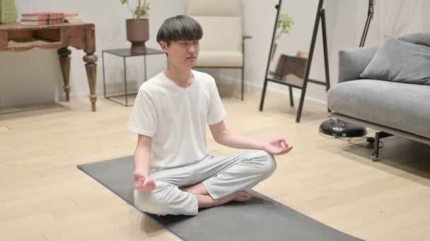aziatische man mediteren op yoga mat thuis - Video