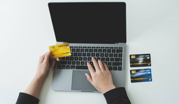 Az üzletasszonyok kezében hitelkártya van, és laptopot használ az online vásárláshoz és az internetes fizetéshez.. - Fotó, kép
