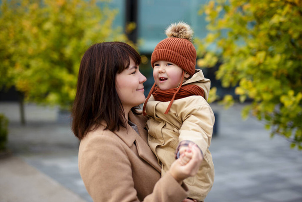 familie, ouderschap, liefde en geluk concept - lachende moeder en haar dochtertje wandelen in het najaarspark - Foto, afbeelding