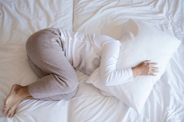 eine junge asiatische Frau schläft bequem im Bett mit einem Kissenbezug auf ihrem Gesicht. im Hotelzimmer, es ist eine schöne Pause während des Urlaubs. Ansicht von oben. - Foto, Bild