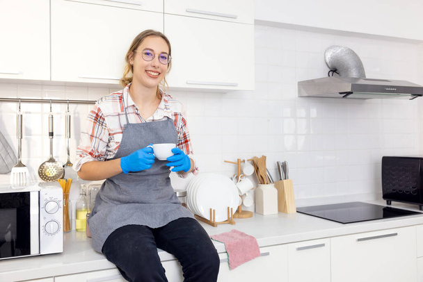 молода красива стильна жінка тримає білий кухоль на білій кухні після склеювання, молода жінка розслабляється
, - Фото, зображення