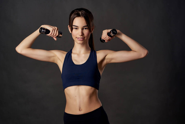athletic woman slim figure dumbbells in the hands of fitness pumped up muscles - Foto, Imagem