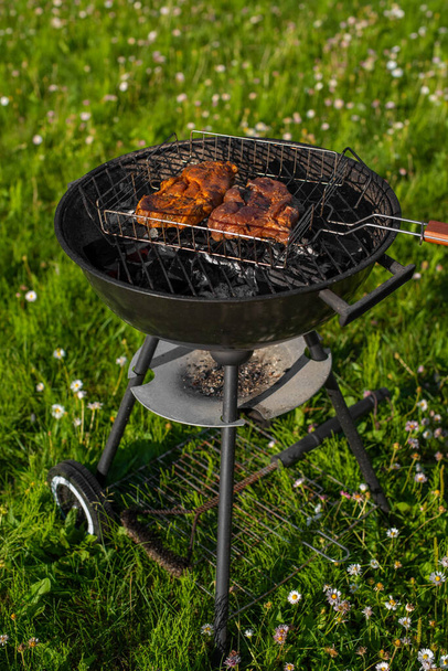 Gekruid varkensvlees op de grill. Vlees buiten grillen op een barbecue. Grillparty in het zomerseizoen. Zonnige zomeravond. - Foto, afbeelding