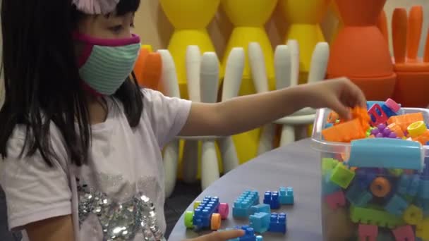 Klein kind dragen gezichtsmasker spelen lego blok aan tafel - Video
