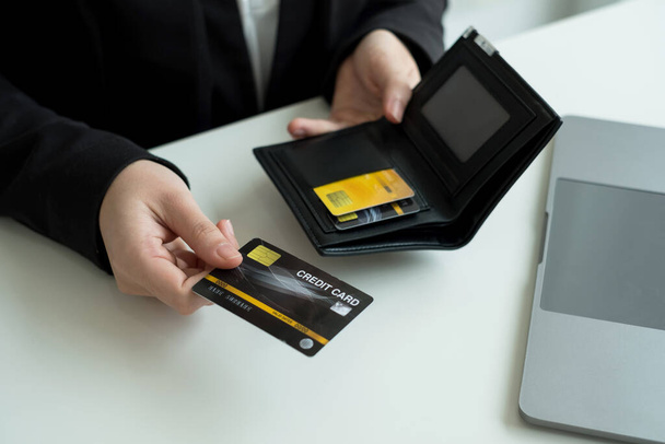 Το χέρι του επιχειρηματία κρατά μια πιστωτική κάρτα και χρησιμοποιώντας ένα φορητό υπολογιστή για online αγορές και πληρωμή στο διαδίκτυο. - Φωτογραφία, εικόνα