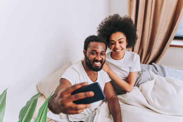 Afro american couple in bed - Real beautiful and cheerful pair of lovers at home - Foto, imagen