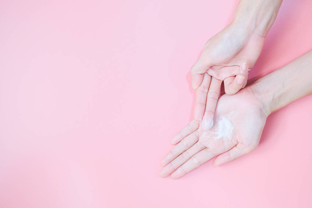 Žena nanášení hydratační krém na ruce na ruce s růžovým pozadím, Zdravotní péče koncept. - Fotografie, Obrázek
