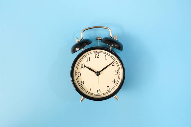 Black vinatge alarm clock with blue background. - Photo, image