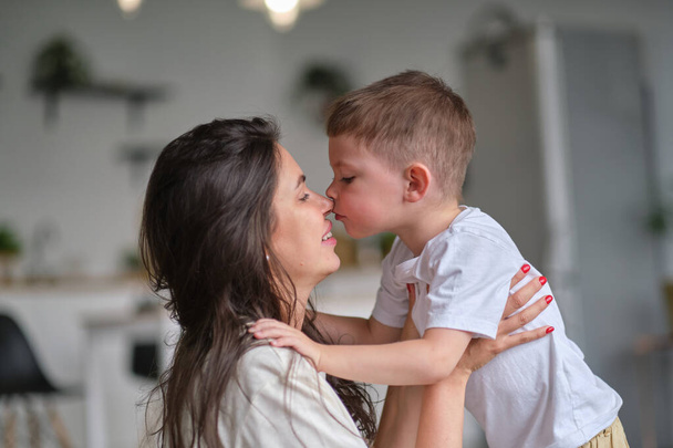 Il ragazzino bacia sua madre dentro. carino bambino baci mamma sul naso. - Foto, immagini