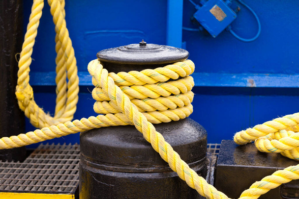 Κίτρινα πηνία ελλιμενισμού σε μαύρο βαρούλκο λεπτομέρεια εξοπλισμού πλοίων - Φωτογραφία, εικόνα