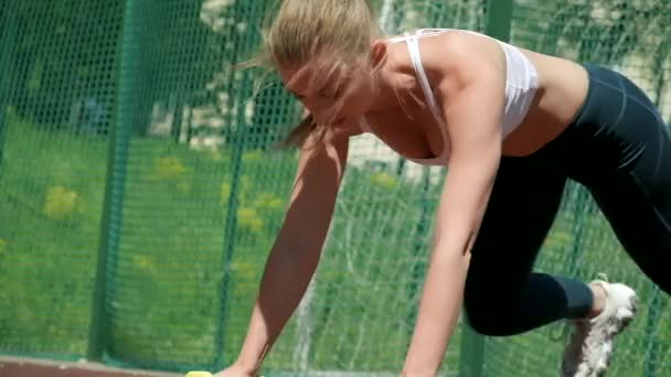 mladá atletická běloška ve sportovním oblečení dělá kliky s činkami - Záběry, video