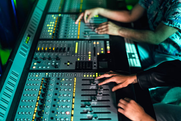 音楽レコーディングスタジオでパネルミキサーコントロールを使用してオーディオエンジニアの手を閉じます - 写真・画像