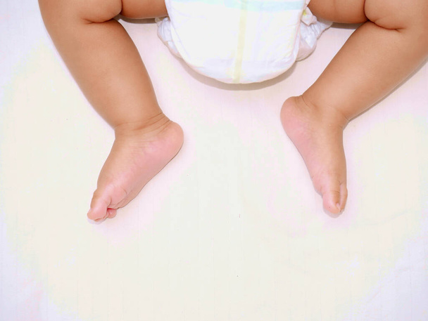 Nowo narodzone nogi z pieluchowym wizerunkiem dla dzieci koncepcja stylu życia. - Zdjęcie, obraz