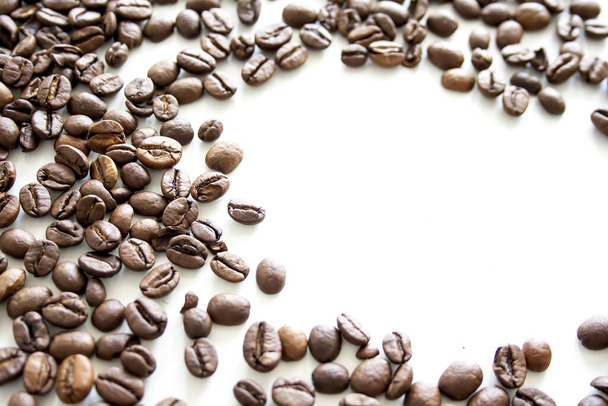 A high angle shot of roasted coffee beans on a white surface - Fotó, kép