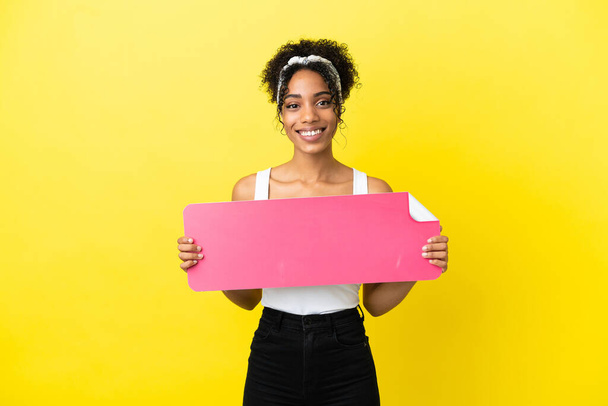 Young african american woman isolated on yellow background holding an empty placard - Φωτογραφία, εικόνα