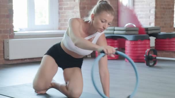 mladý kavkazský fit sportovní žena dělá prkno cvičení s pilates kroužek v tělocvičně - Záběry, video