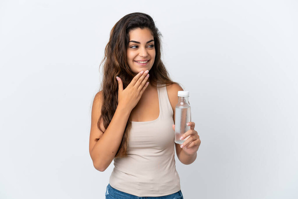 Beyaz arka planda izole edilmiş bir şişe suyu olan beyaz bir kadın gülümserken yukarı bakıyor. - Fotoğraf, Görsel