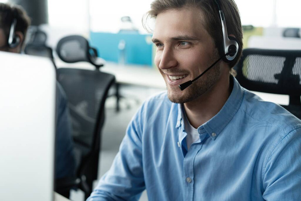 Young handsome male customer support phone operator with headset working in call center - Foto, Bild
